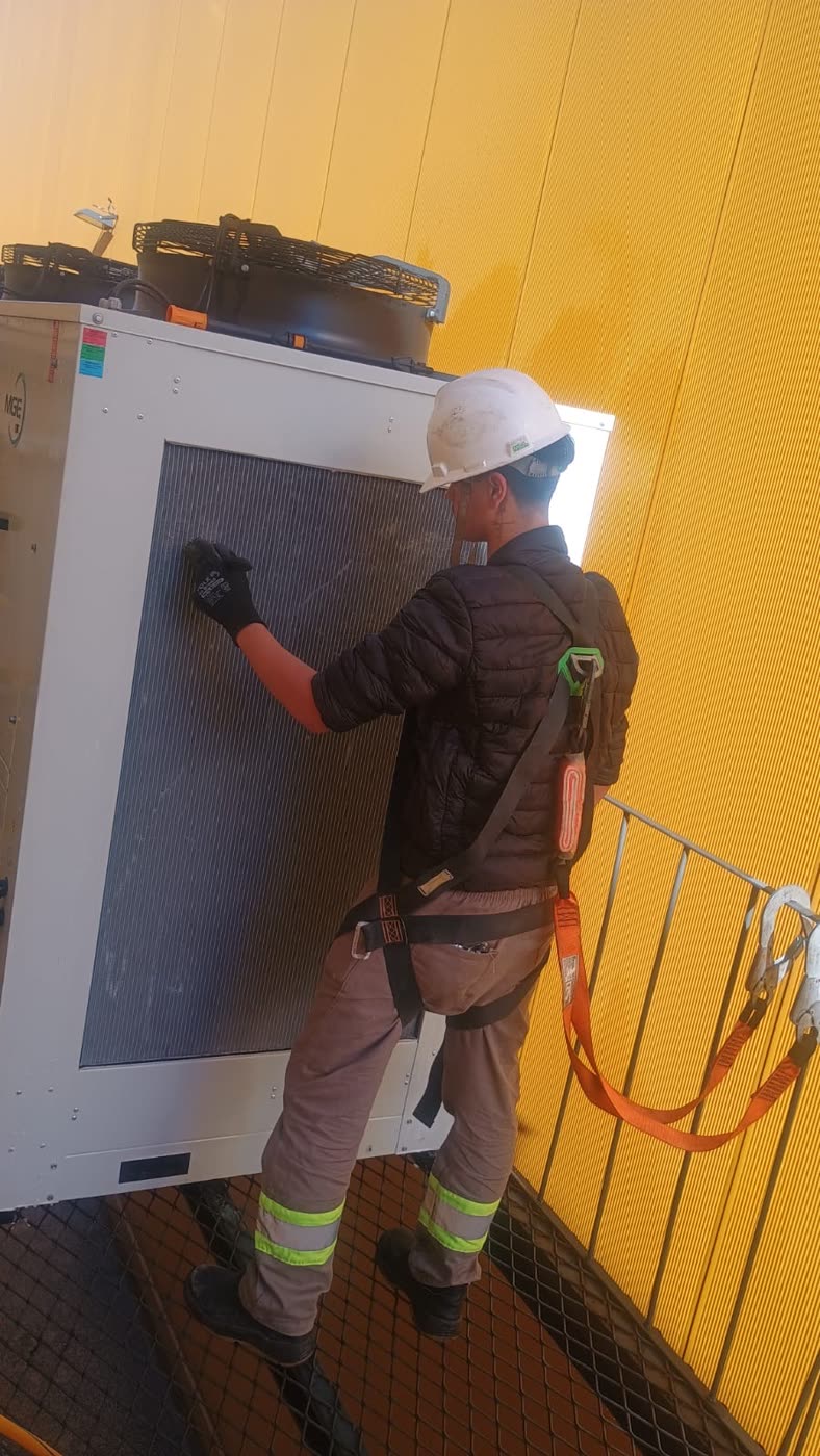 Técnico da Help Home com EPI e cinto de segurança fazendo manutenção na condensadora