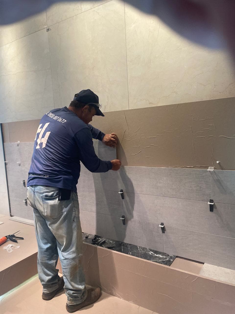 Técnico da Help Home assentando revestimento cerâmico na parede